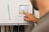 Ein evm Handwerker befindet sich in einem Keller und steht vor einem Speicher. Er zeigt auf den Bildschirm des Speichers.