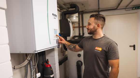 Ein evm Handwerker befindet sich in einem Keller und steht vor einem Speicher. Er zeigt auf den Bildschirm des Speichers.