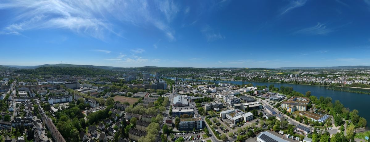 Koblenz-Rauental Panoramablick über ein Stadtgebiet in Koblenz mit Wohnquartieren, Bürogebäuden, Gewerbeflächen und dem Rhein im Hintergrund.