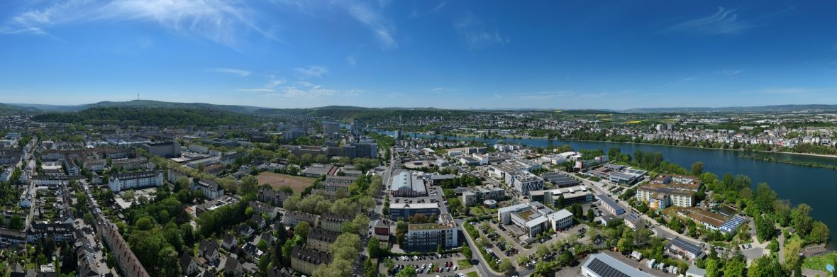 Koblenz-Rauental Panoramablick über ein Stadtgebiet in Koblenz mit Wohnquartieren, Bürogebäuden, Gewerbeflächen und dem Rhein im Hintergrund.
