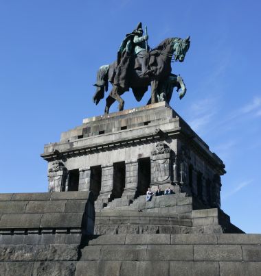 Das Kaiser-Wilhelm-Denkmal auf seinem steinernen Sockel vor blauem Himmel am Deutschen Eck in Koblenz.