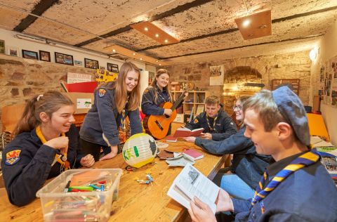 Eine Gruppe von Pfadfindern sitzt bei gemeinsamen Aktivitäten zusammen.