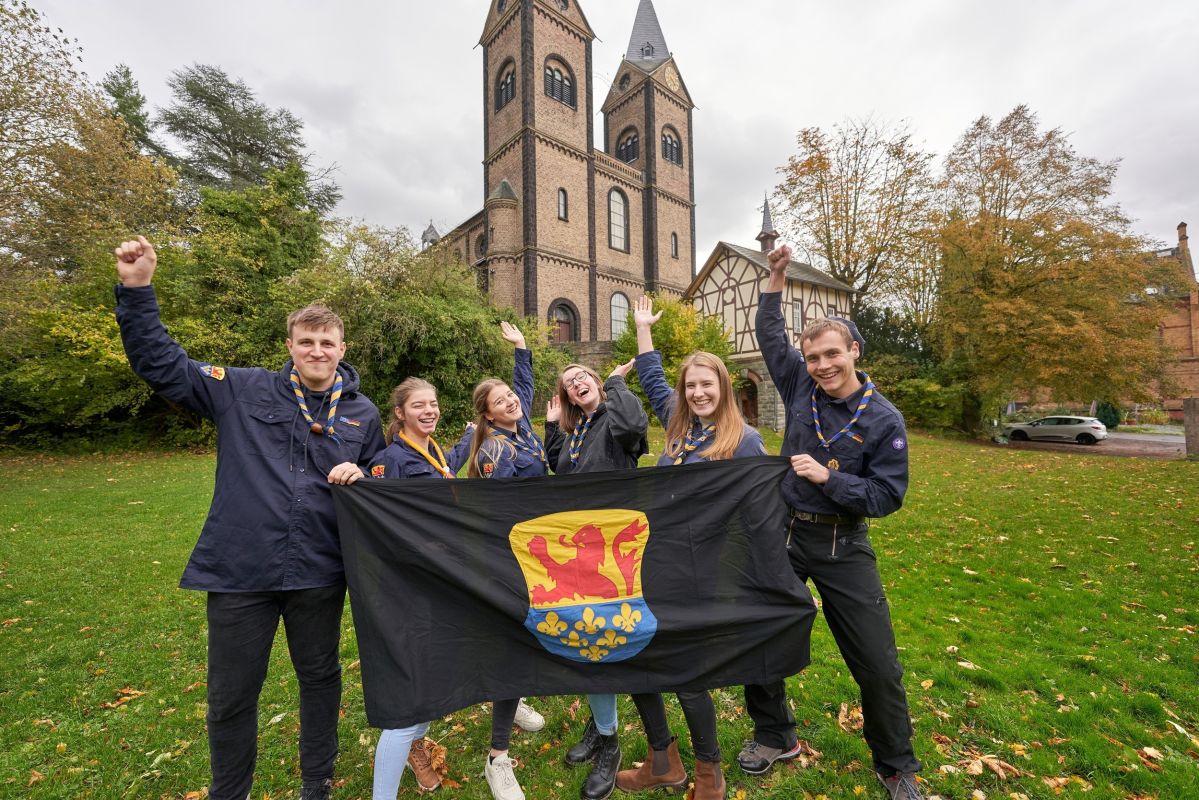 Sechs Jugendliche des Pfadfinderstamms freuen sich gemeinsam über ihren Preis und halten ihr Wappen in der Hand.