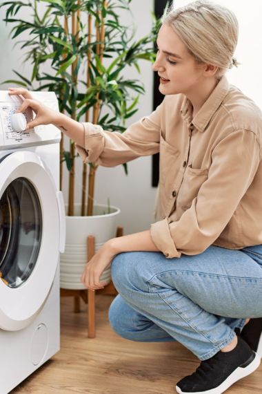 Young caucasian woman smiling confident washing clothes at laundry room