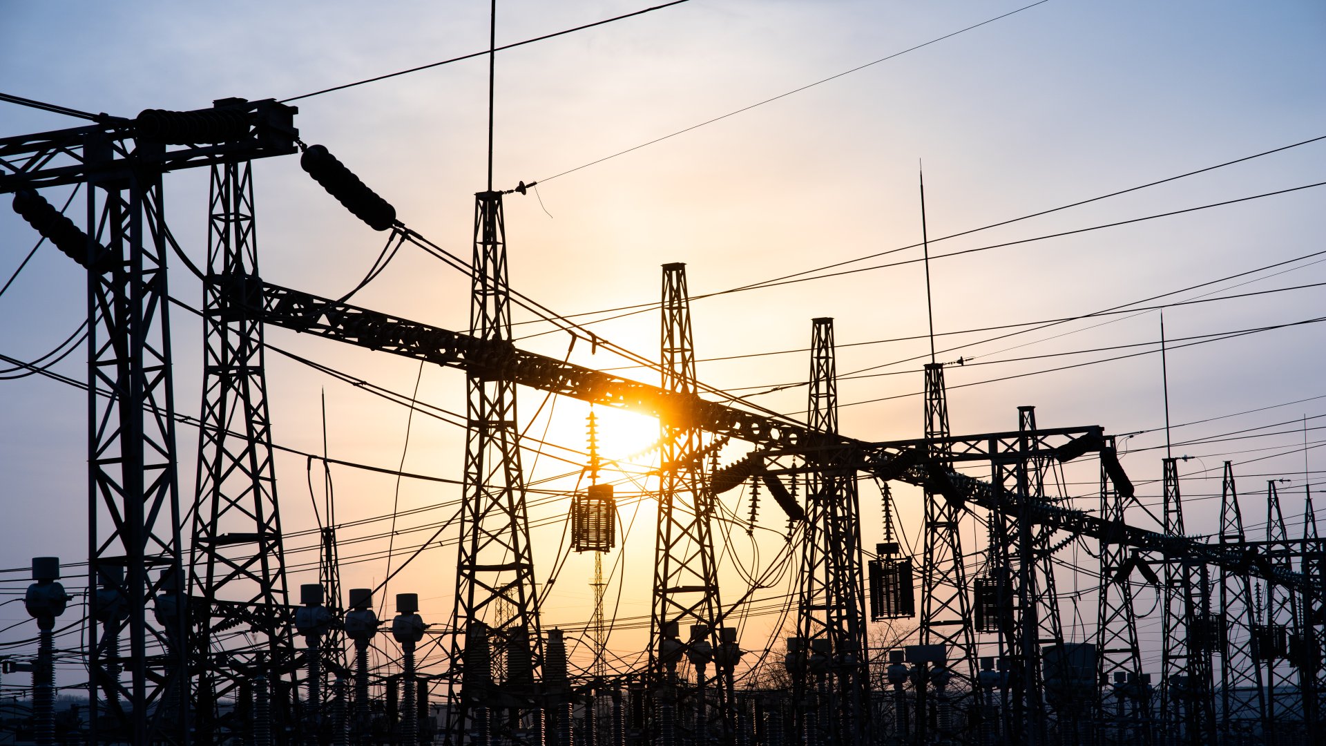 Impression network at transformer station in sunset, high voltage up to blue sky take with blue tone, horizontal frame. electrical distribution stations