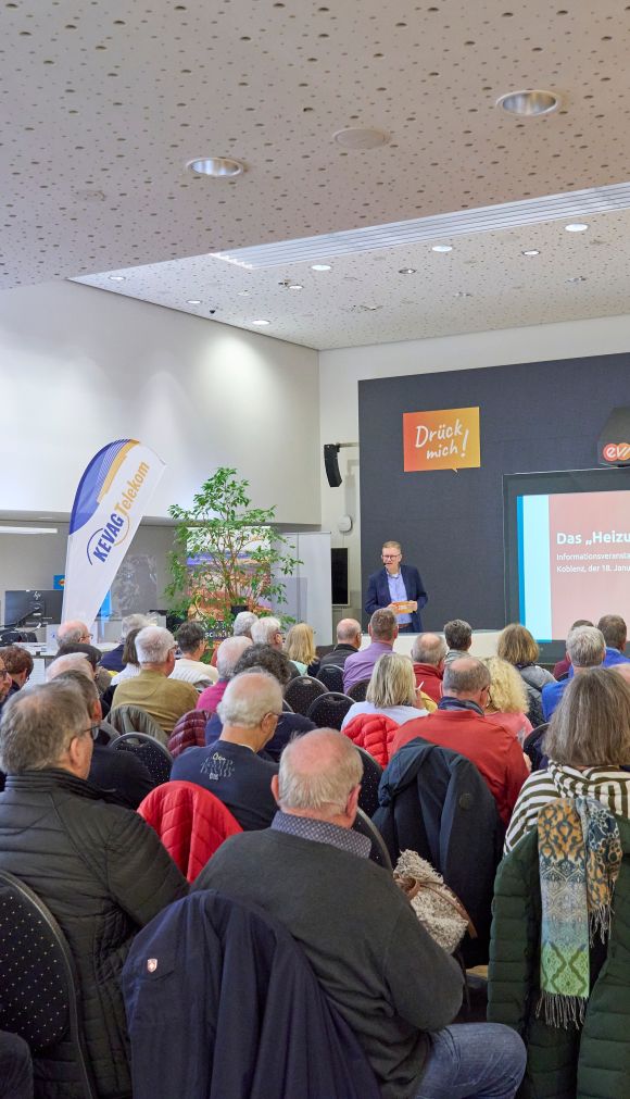 240124SDI1001 Ein Publikum sitzt in einem Saal. Vor ihnen steht ein professionell gekleideter Mann und präsentiert..