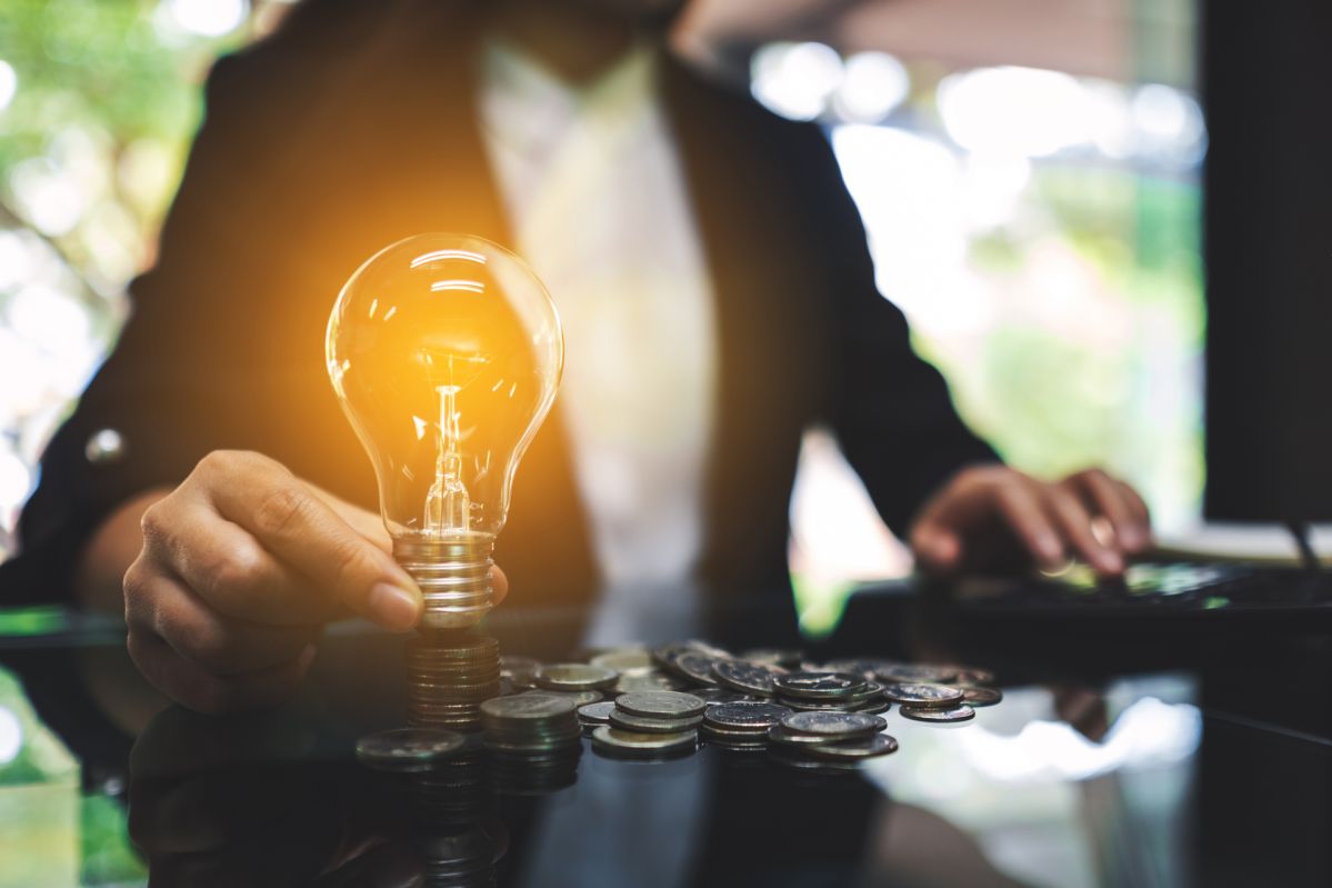 Senkung Strompreise Koalitionsvertrag 2025 Businesswoman putting a light bulb over coins stack on the table while calculating for saving energy and money concept
