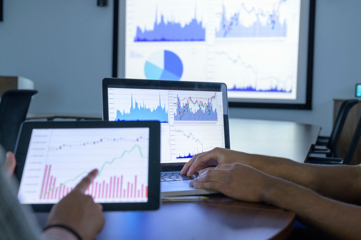 Businessman and woman using screens with graphs and charts in business meeting, close up Eine Besprechung, in der Ipads eingesetzt werden