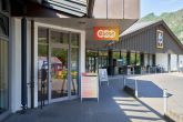 evm-Kundenzentrum Cochem Ein Bürogebäude mit zwei Eingängen, mit einem "EVM"-Schild links und einem "Aldi"-Schild rechts. Fahrräder sind rechts geparkt. Sonnenlicht scheint auf den Gehweg.