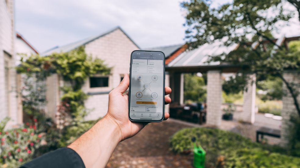 Einbau Wärmepumpe und PV Kunde Suwelack Eine Hand hält ein Handy, auf dem der Smart-Home-Manager zu sehen ist.