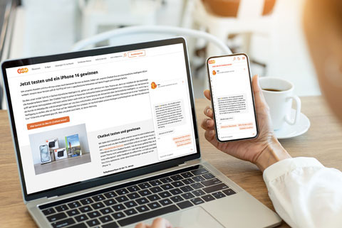 Eine Person hält ein Handy in der Hand und vor ihr steht ein Computer