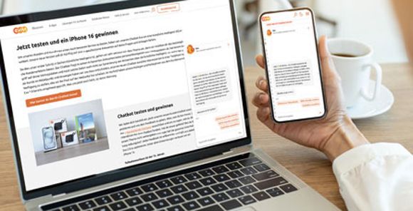 Eine Person hält ein Handy in der Hand und vor ihr steht ein Computer