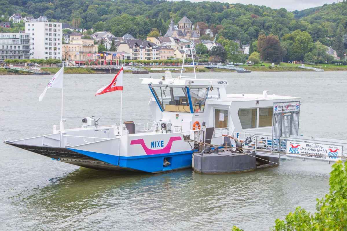 Schmidt-bild-69 Eine blau-weiße Fähre mit einem pinken Logo liegt an einer Anlegestelle.