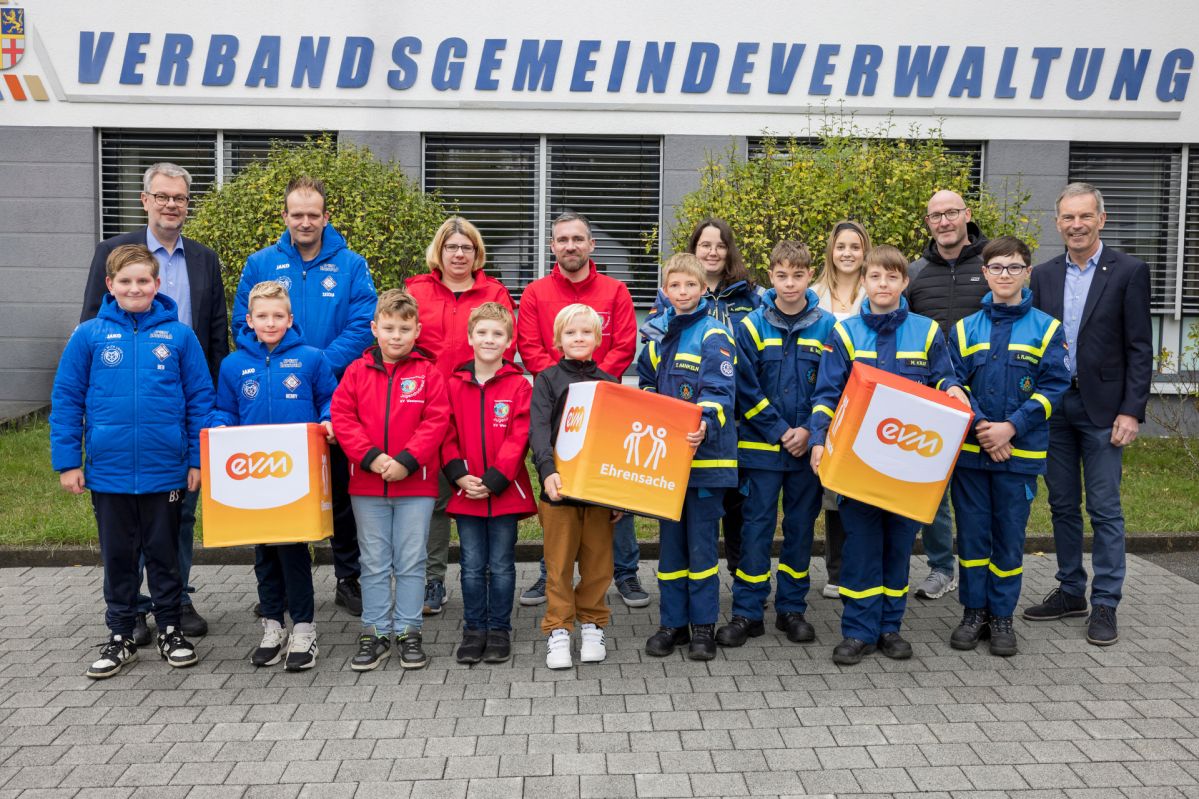 Spendenübergabe der evm-Ehrensache an Vereine aus der Verbandsgemeinde Westerburg. Kinder und Erwachsene verschiedener Vereine, wie z.B. THW stehen mit dem Bürgermeister nebeneinander. Sie alle bekommen eine Spende der evm im Rahmen der evm-Ehrensache.