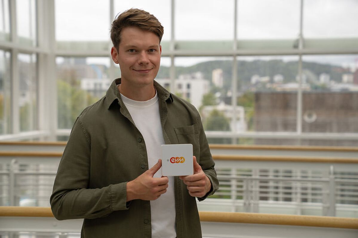 evm-Innovationsmanager Nicolai Kretz hält eine weiße Box in der Hand. Das ist der neue evm+Energiepilot, der Energiepilot für dein Zuhause.