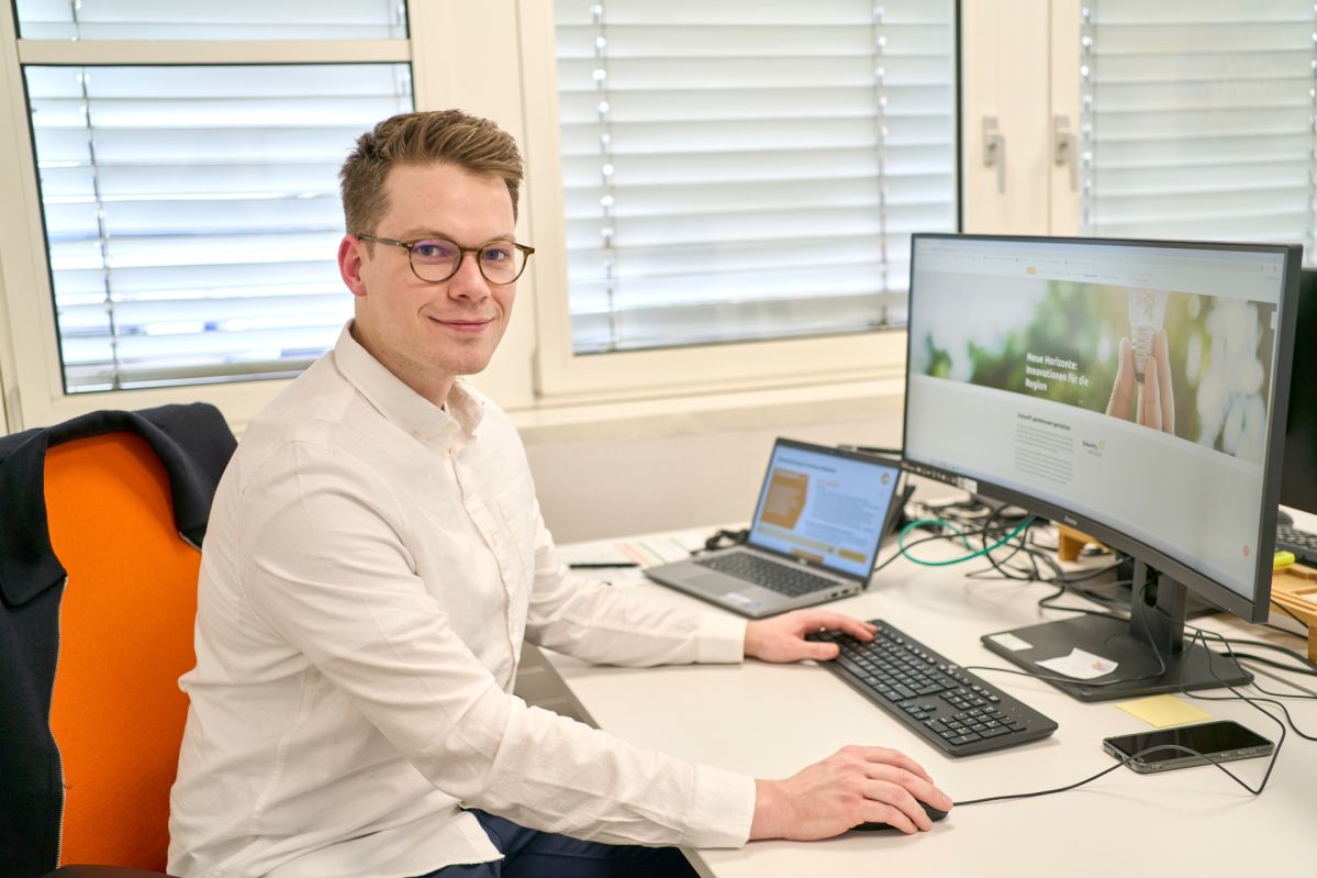 Nicolai sitzt an seinem Schreibtisch, vor ihm der Computer.