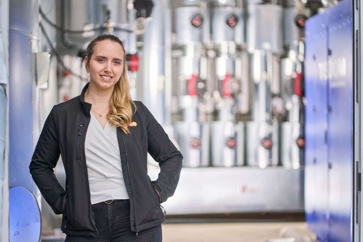 Vom Praktikum zur Projektleitung Nadine Kuhlmann vor technischen Anlagen: In einem industriellen Umfeld mit Rohrleitungen und Ventilen zeigt sich ihr Einsatz für eine nachhaltige Wärmeversorgung.