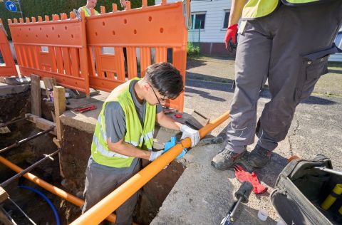 Arbeiten am Gasnetzanschluss in Lahnstein: Zwei enm-Monteure installieren Rohre aus Polyethylen in gesicherter Baustelle.